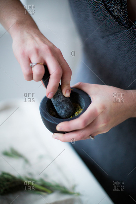 Close-up of woman's hands using mortar and pestle to grind fresh herbs