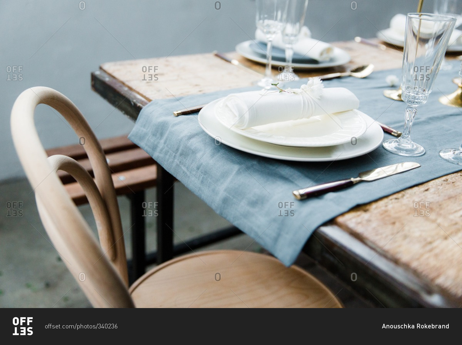 Wooden chair and table with blue linen runner and cream coloured plates
