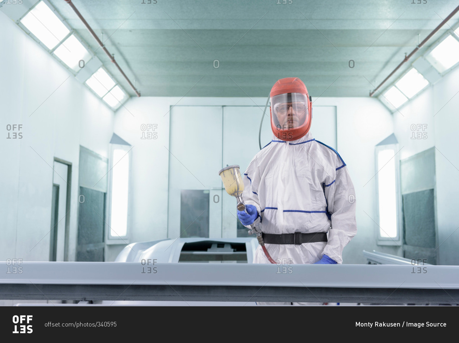 Portrait of worker paint spraying parts on automotive production line