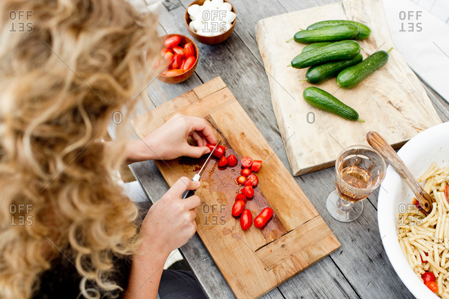 Woman chopping tomatoes on wooden chopping board, high angle