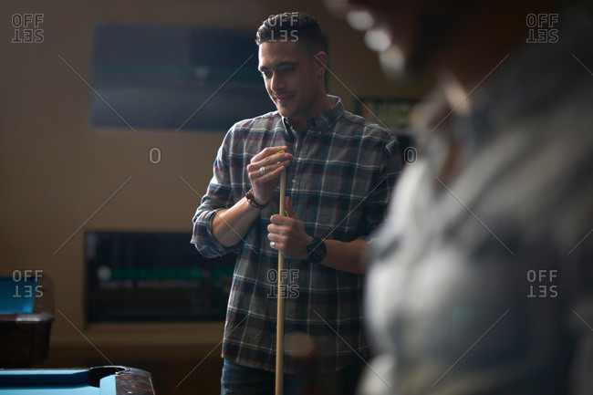 Man with pool cue standing at pool table