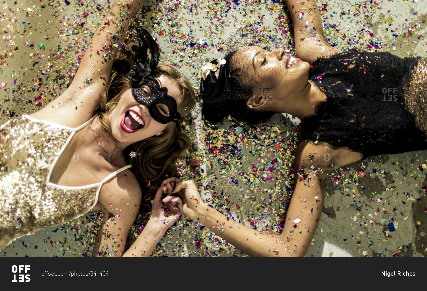Friends lying together on a floor covered in confetti
