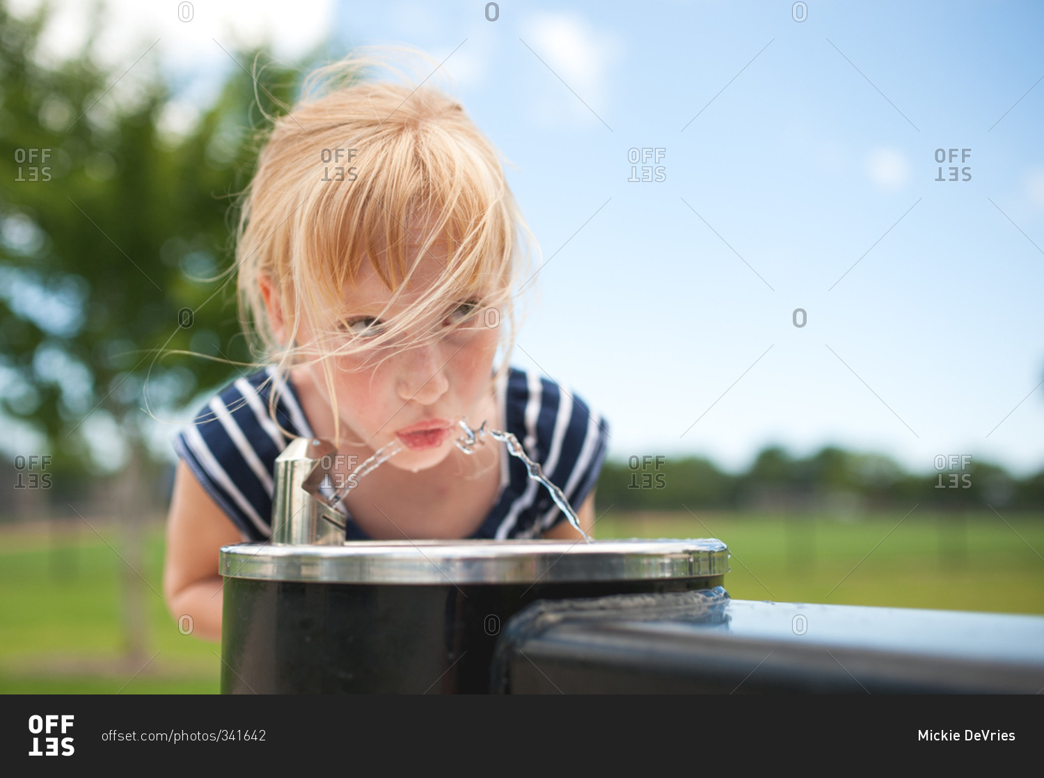 Young girl getting drink from outdoor water fountain
