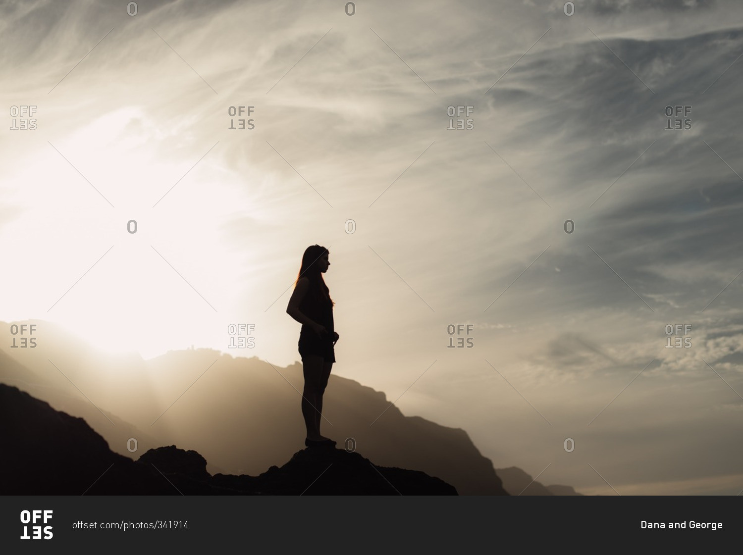 Woman silhouetted on rocks at sunset