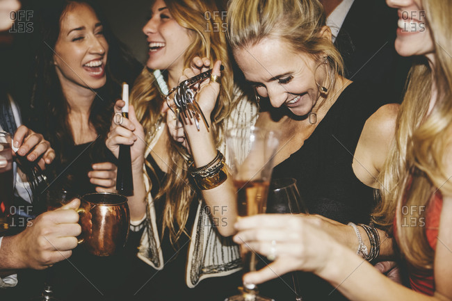 Friends laughing and holding noisemakers at a party