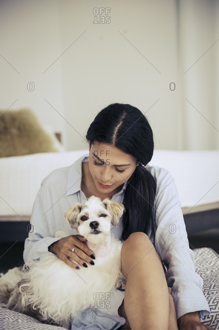 Woman cuddling with a dog on a cushion in a bedroom