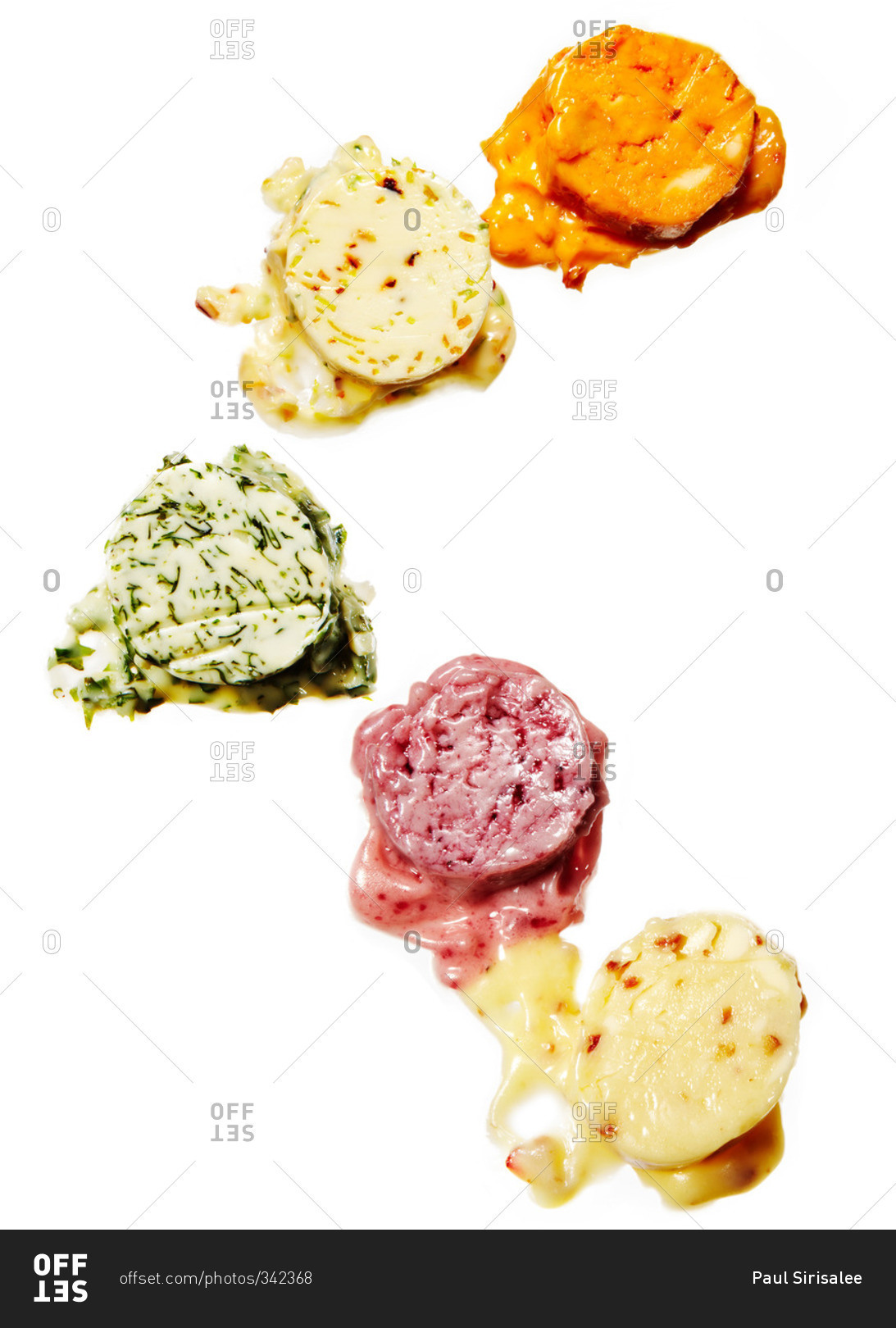 Pats of colorful, savory butter on a white background