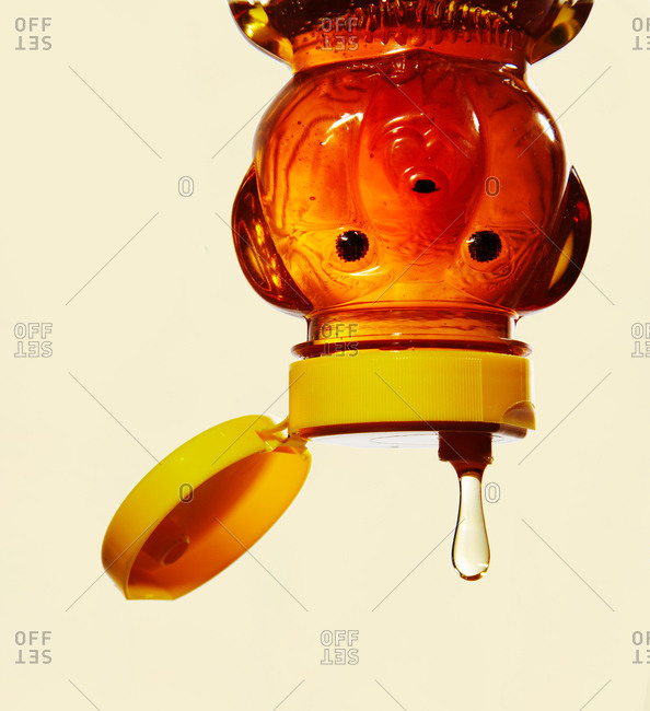 Honey drop coming from an overturned honey bear bottle