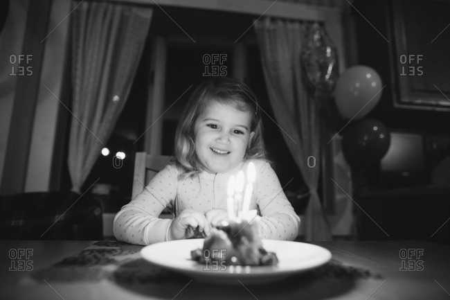 Girl sitting at a table preparing to make a wish at her birthday party