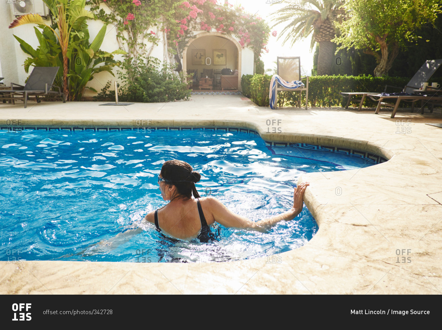 Mature woman swimming in vacation apartment swimming pool