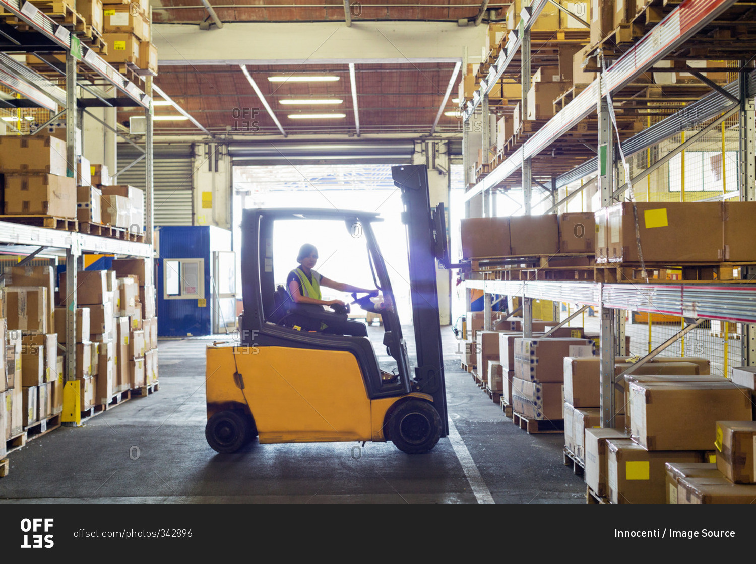 Silhouetted forklift truck at work in distribution warehouse