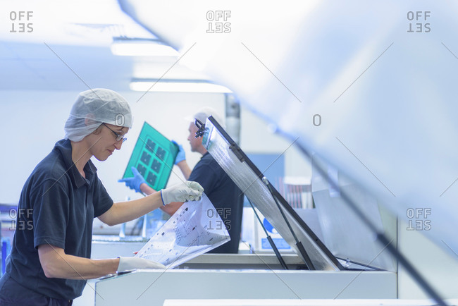 Female worker printing boards in circuit board factory