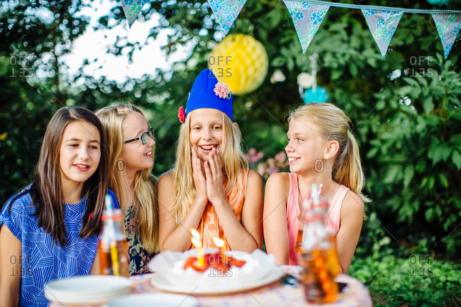 Girl surpised by friends with a birthday cake at summer garden party