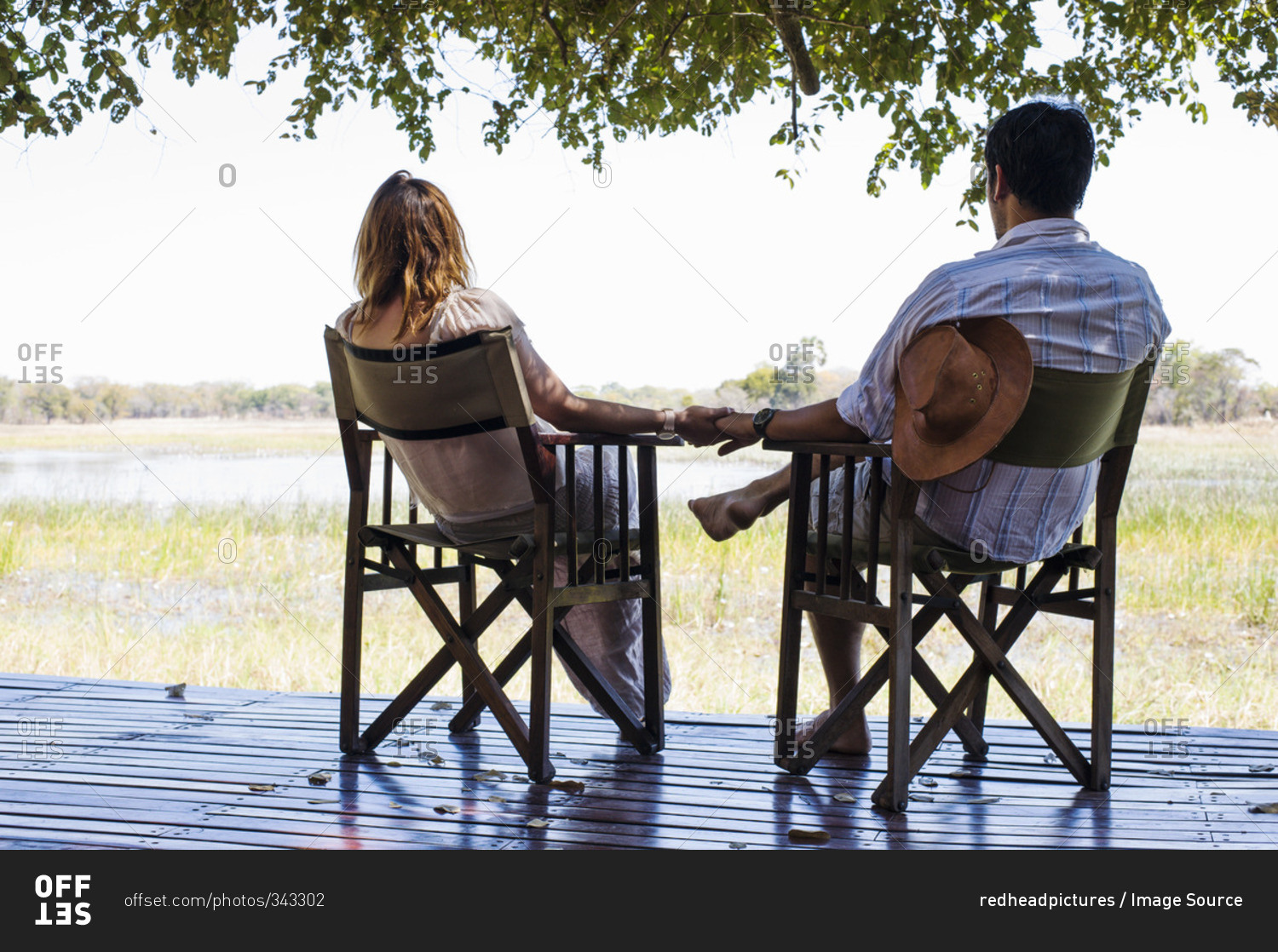 Romantic couple holding hands whilst sitting  at safari lodge, Kafue National Park, Zambia