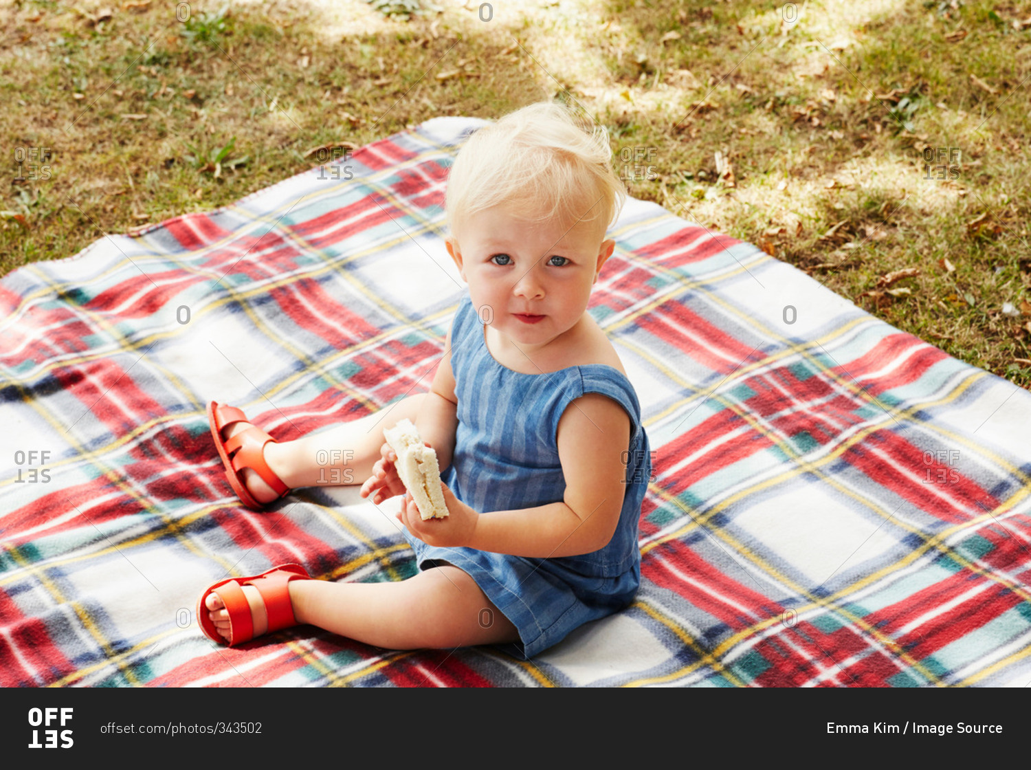 High angle view of baby girl sitting on picnic blanket looking ahead