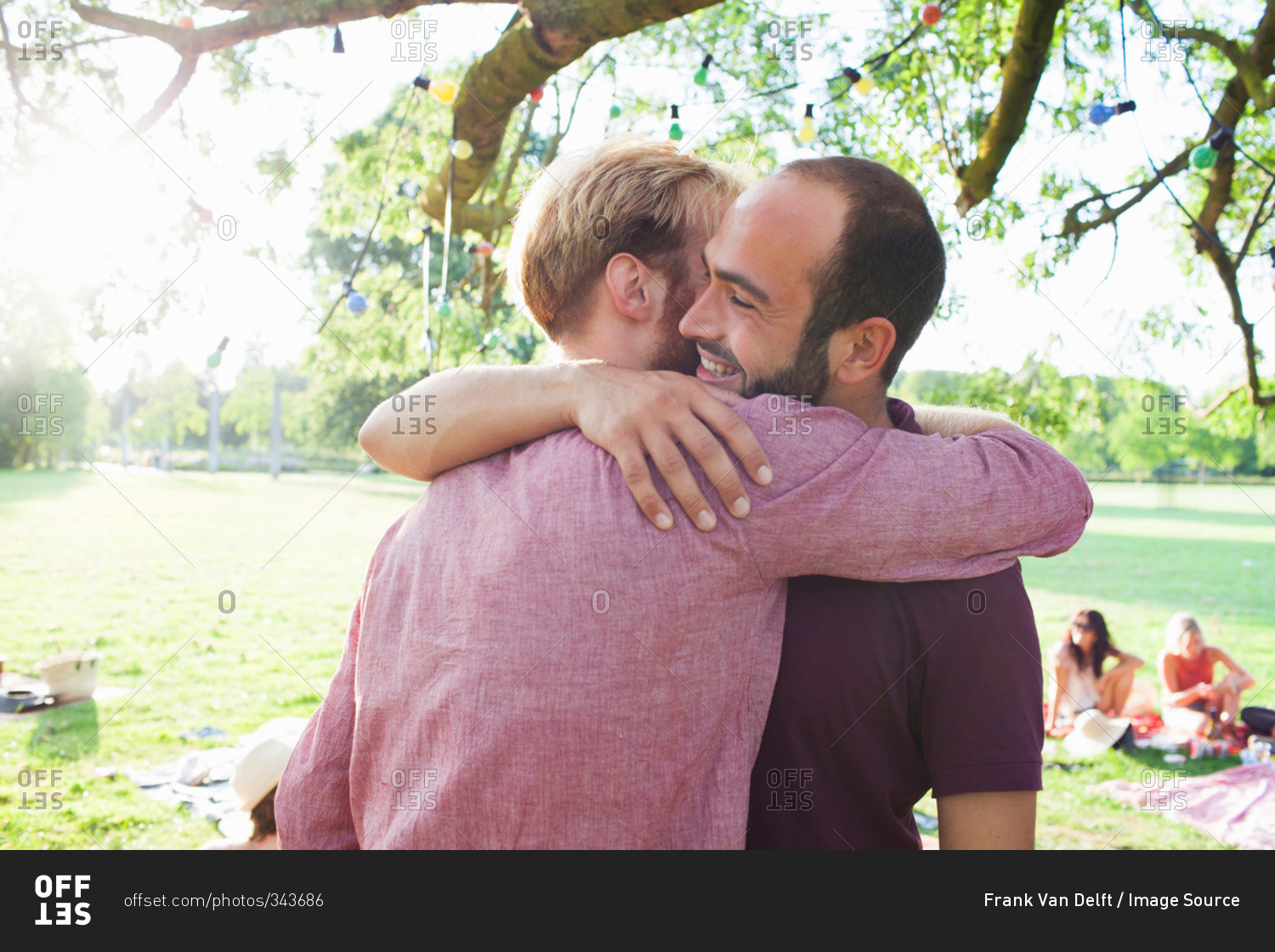 Two young men hugging each other at party in park