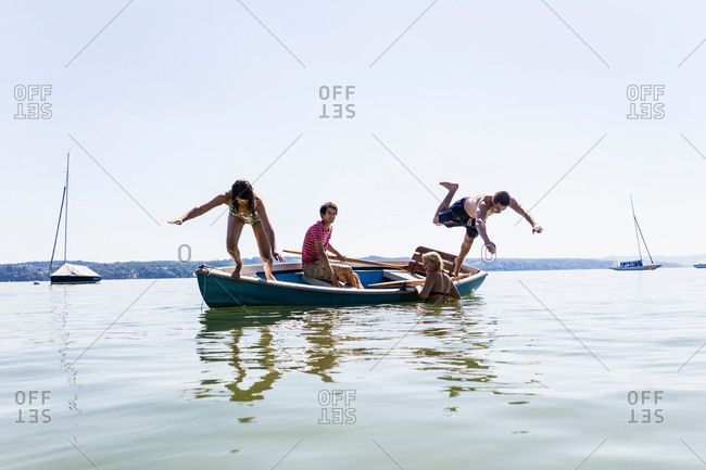 Group of friends diving from boat into lake, Schondorf, Ammersee, Bavaria, Germany