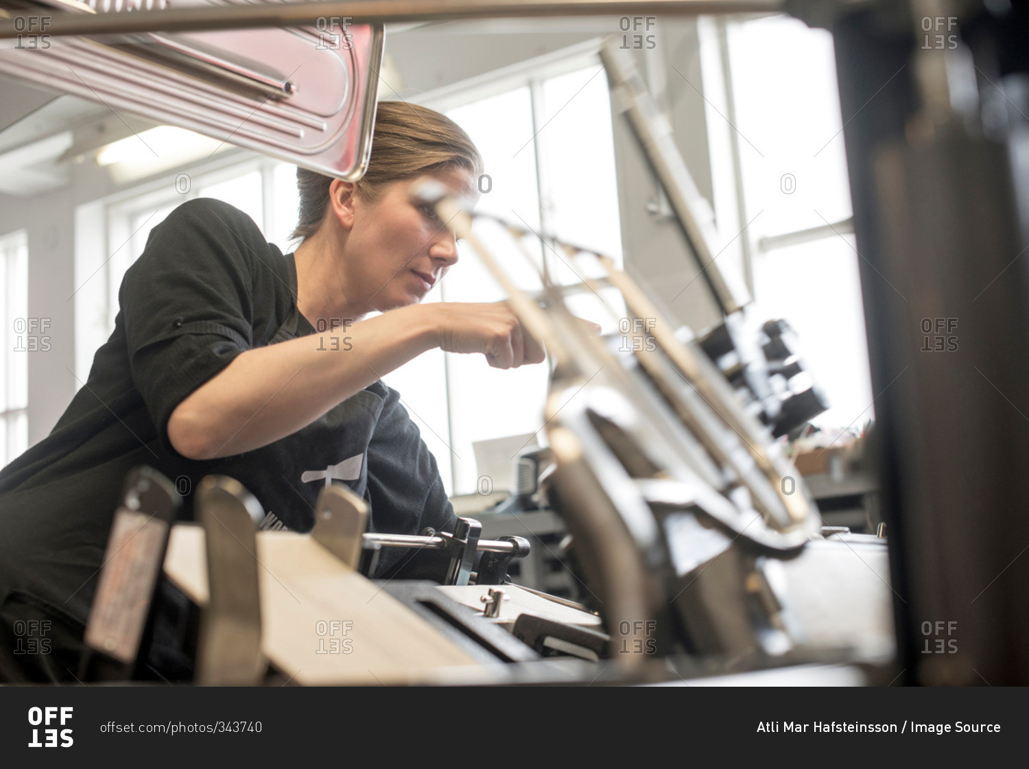Female printer preparing machine in workshop
