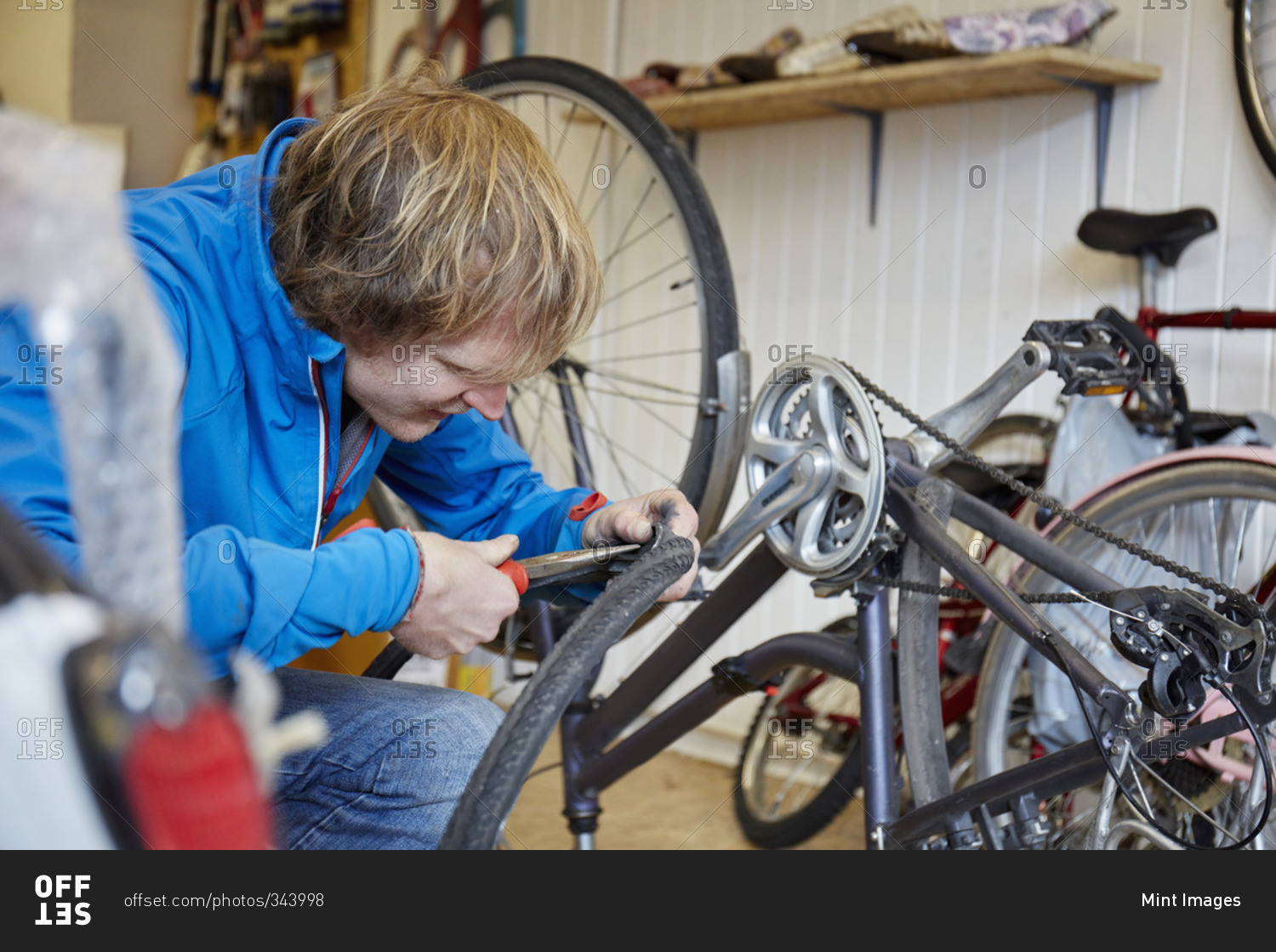 A young man repairing a bicycle in a shop