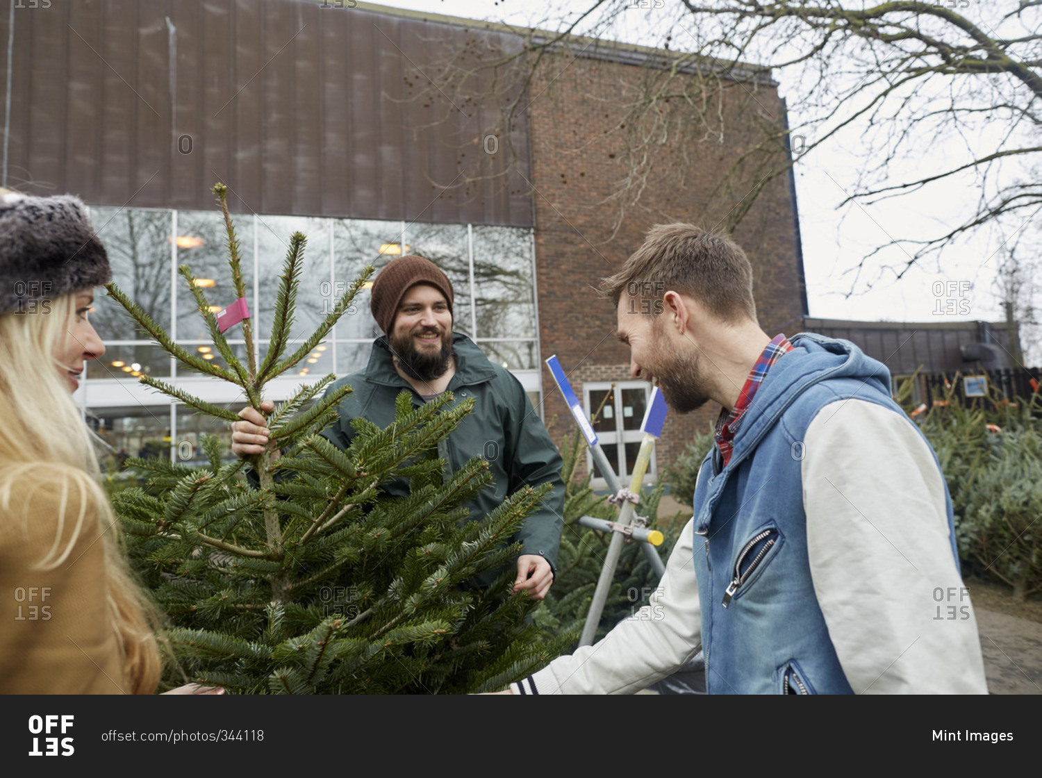 Two staff and a woman client looking at a large Christmas tree