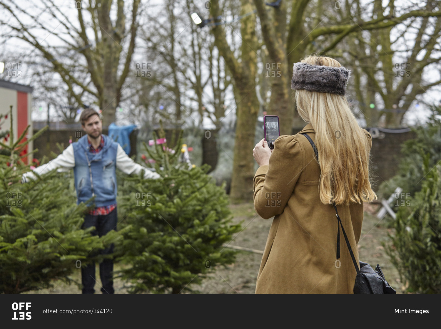 A woman shopping for a Christmas tree, assisted by staff