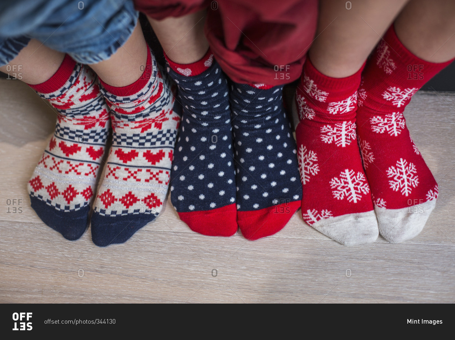 Three pairs of children's feet in bright patterned Christmas socks