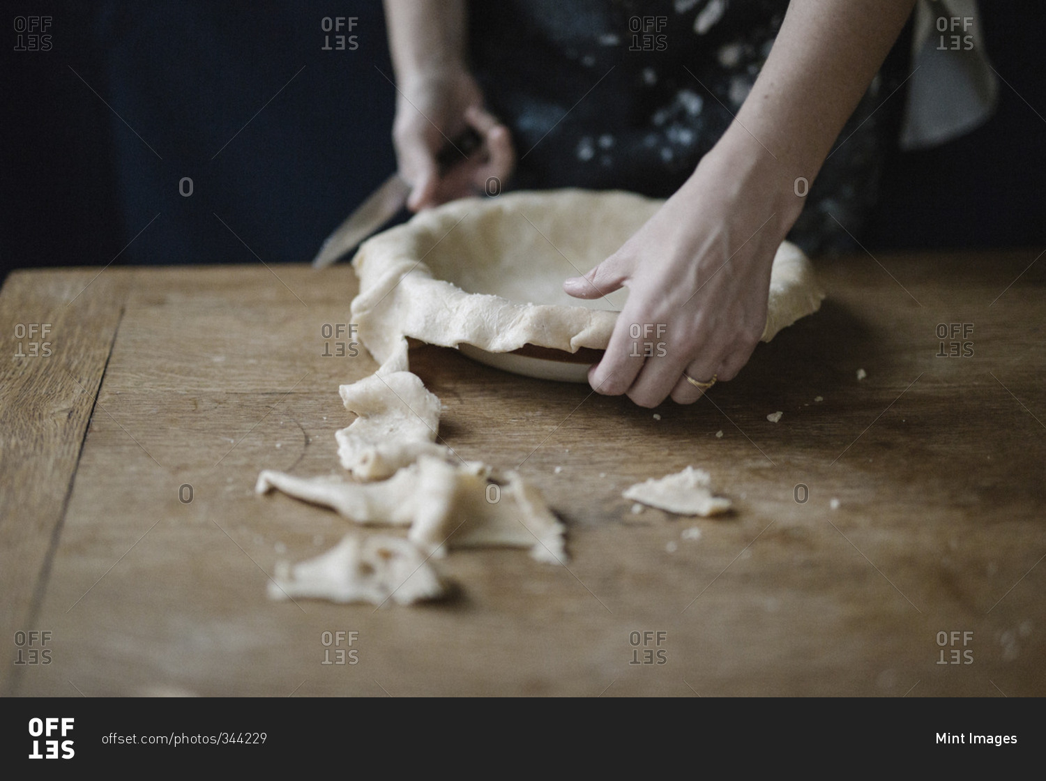 A woman trimming pastry dough to line a pie dish