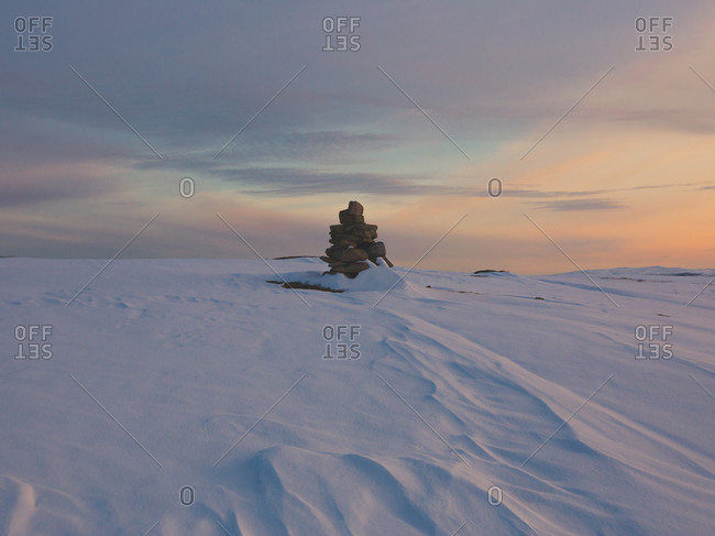 Marker stone and snowdrifts along a barren hillside