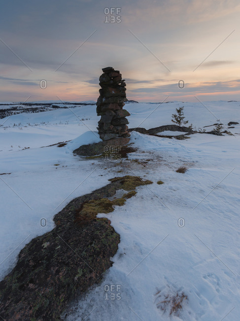 Marker stone and snowdrifts along a barren hillside