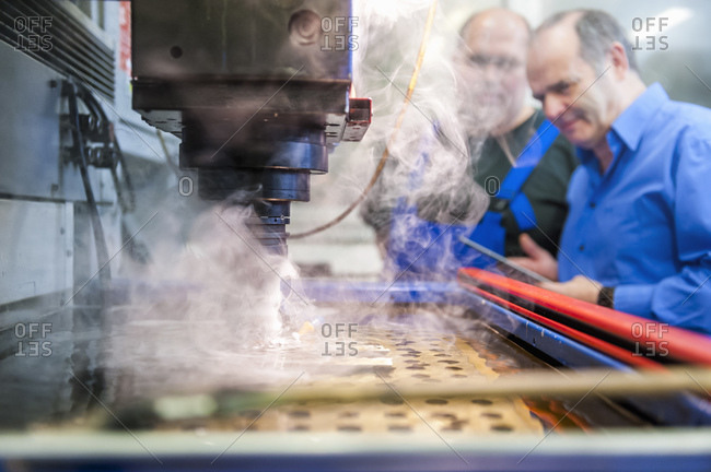 Two men in factory at eroding machine