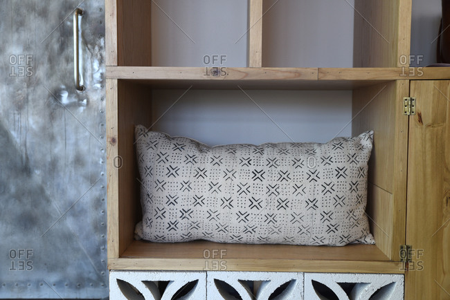 Throw pillow on a wooden shelf
