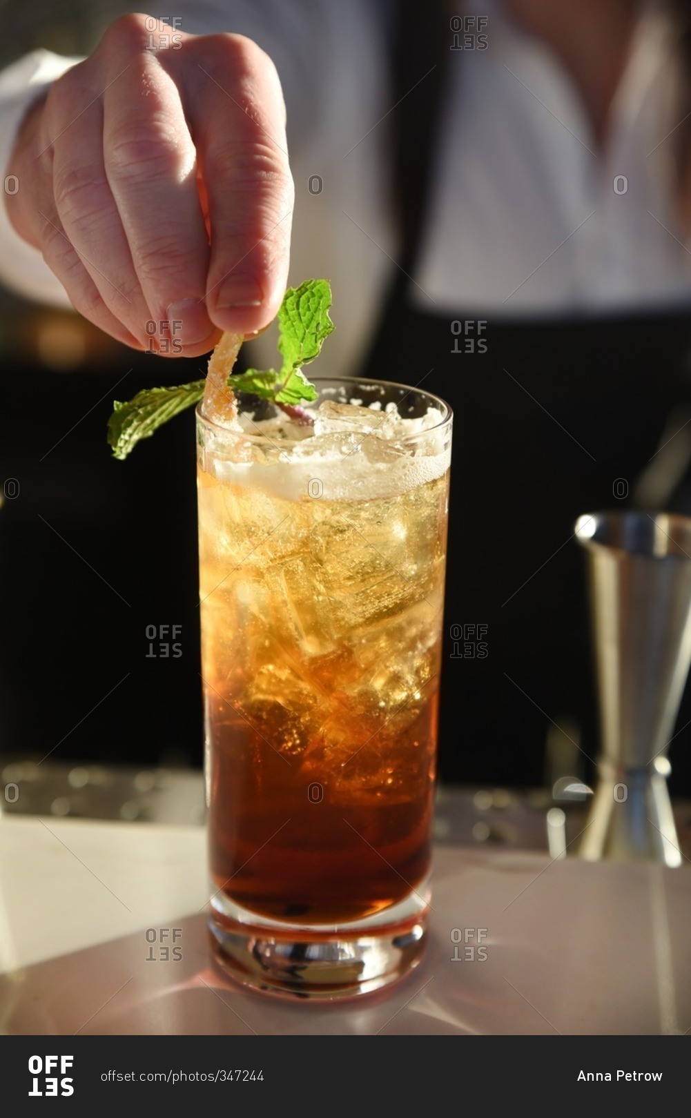 Bartender garnishing a mixed drink on a bar top