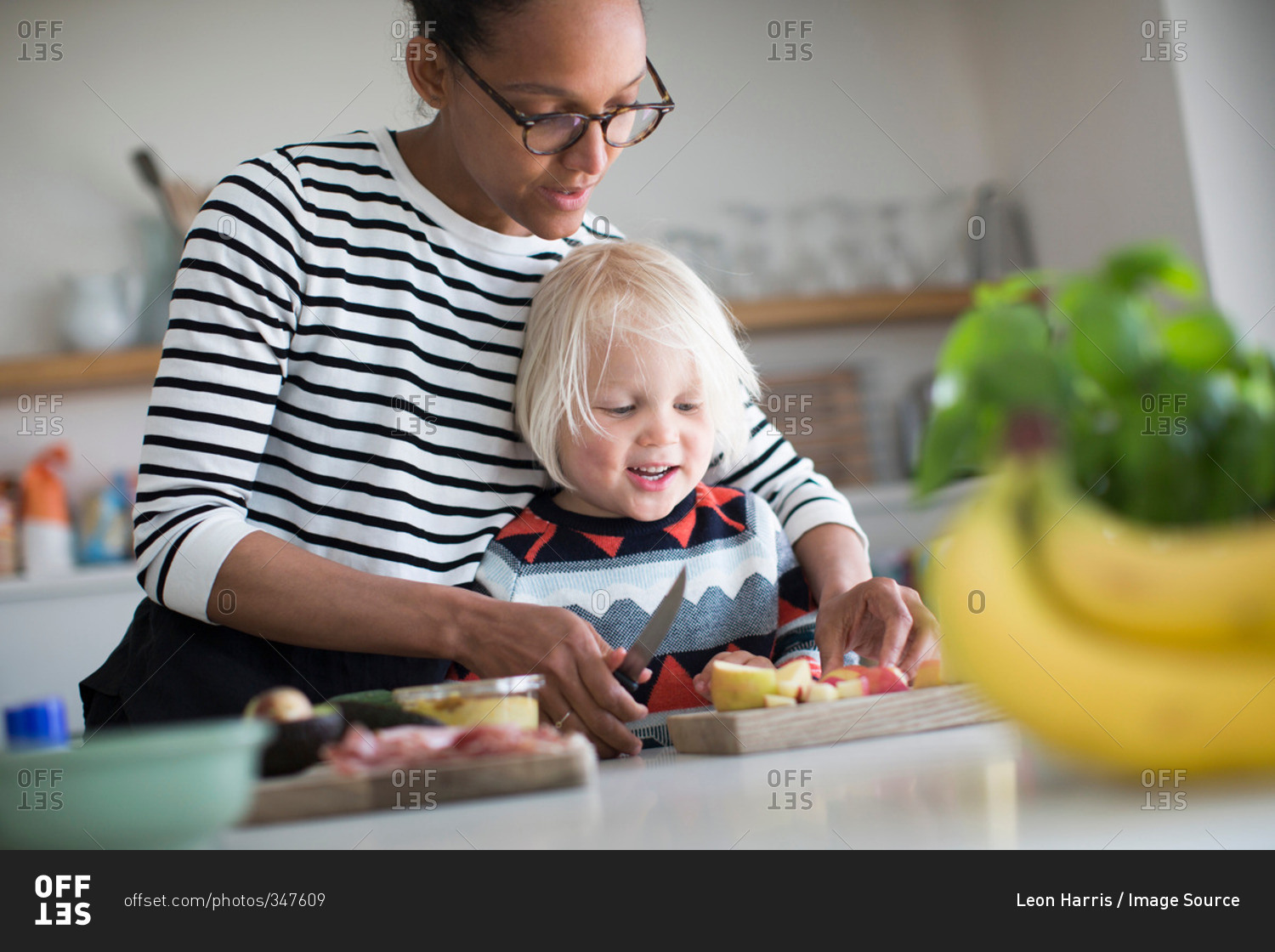 Mother helping son prep food in kitchen