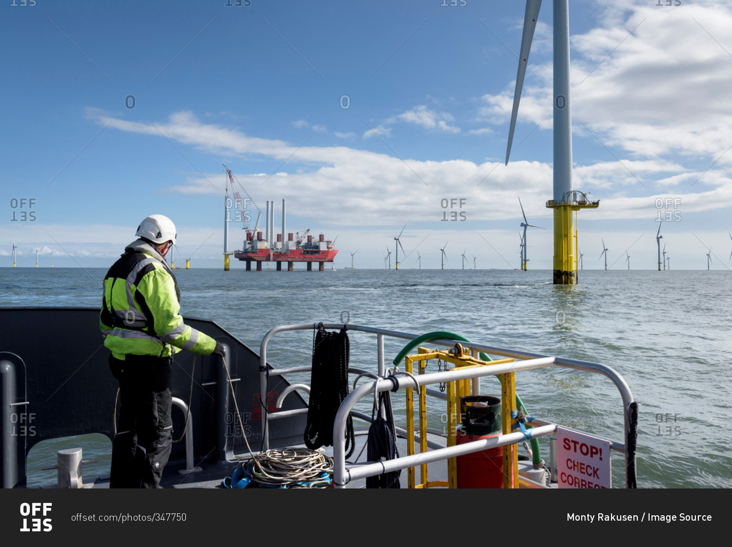 Worker looking out from ship to offshore wind farm and construction ship