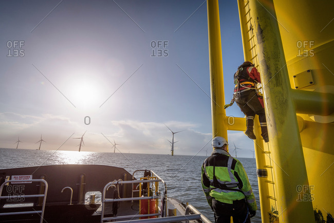 Engineers climbing wind turbine at offshore wind farm
