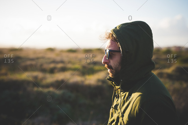 Portrait of mid adult man wearing anorak hood in field