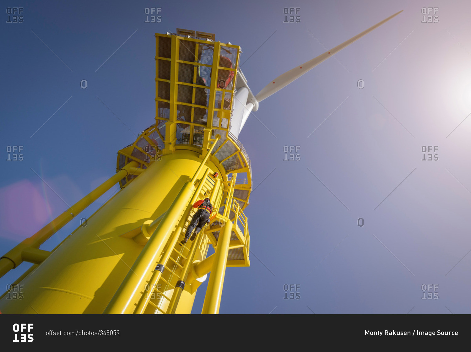 Low angle view of engineers climbing turbine from ship at offshore windfarm