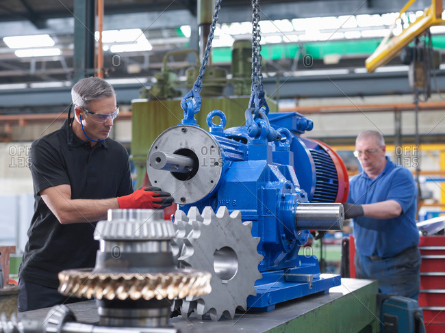 Engineers assembling industrial gearbox in engineering factory