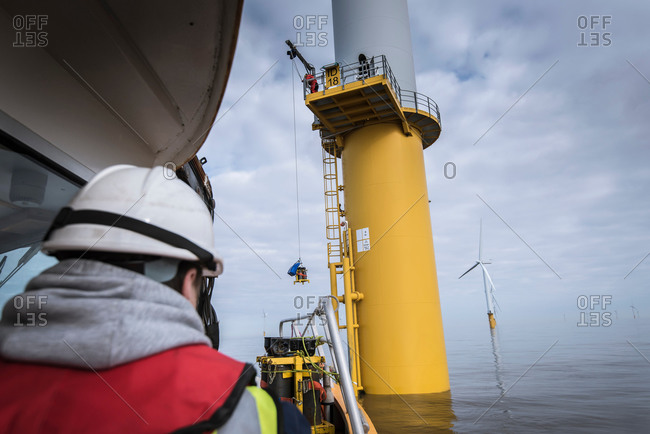 Engineers winching parts up to wind turbine on offshore windfarm