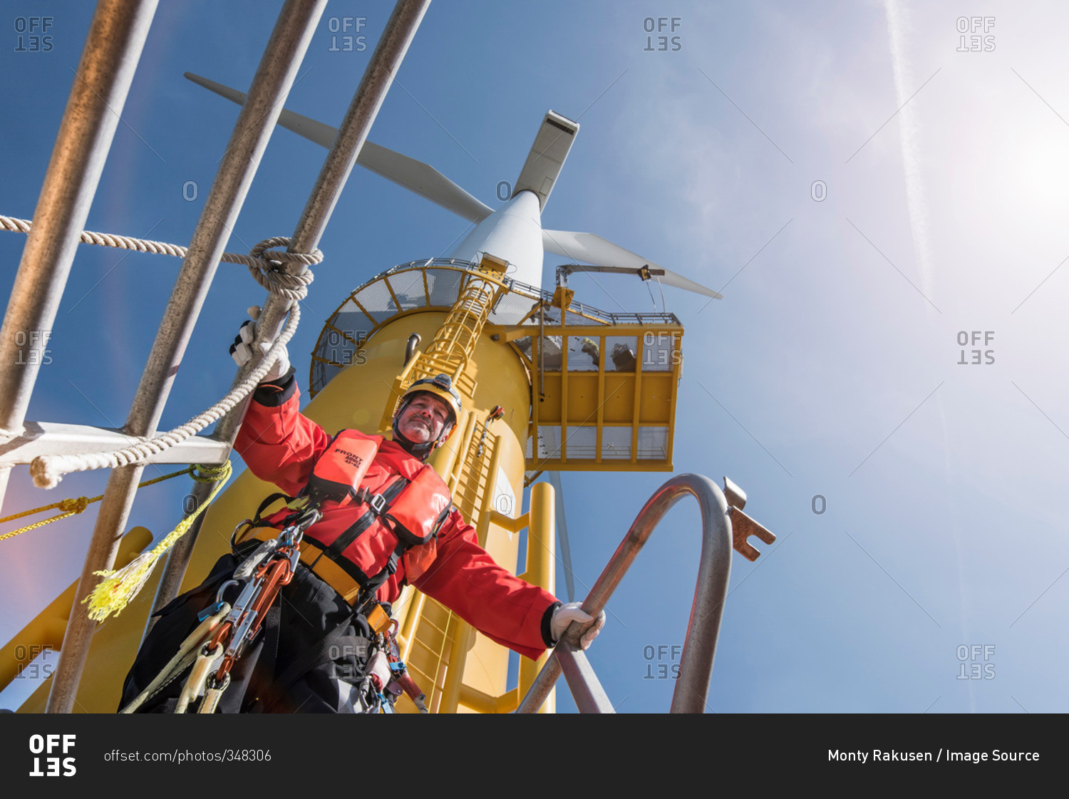 Engineer preparing to climb wind turbine at offshore windfarm, low angle view