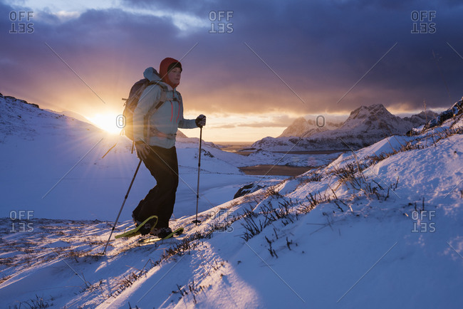 Female hiker with snowshoes at winter dawn on way to Ryten, Moskenesay, Lofoten Islands, Norway