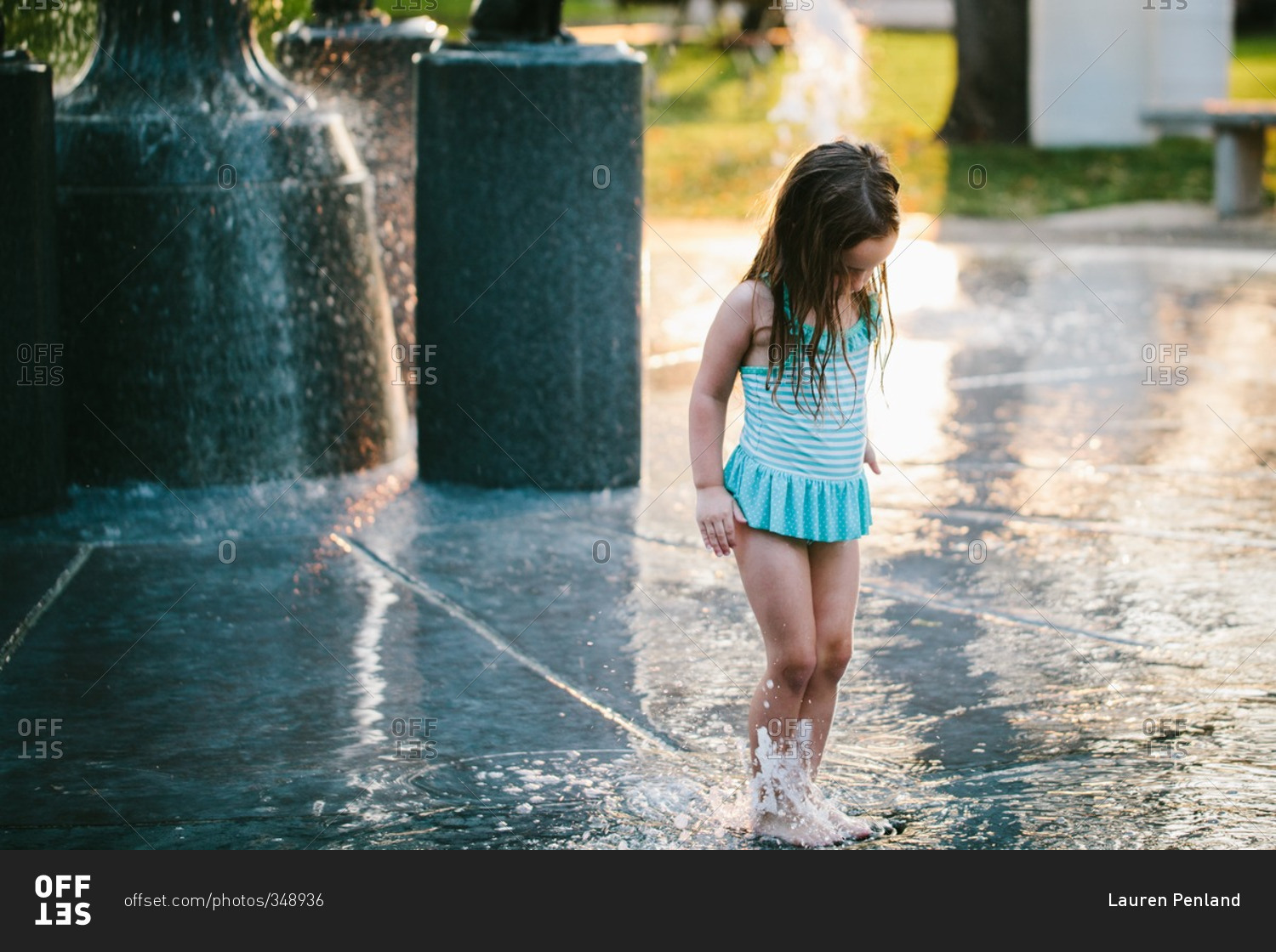 Little girl playing in water at spray park stock photo - OFFSET