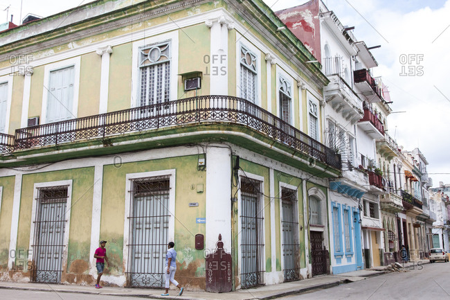 3/18/2016, Cuba: Two people walking on the sidewalk in a densely populated neighborhood