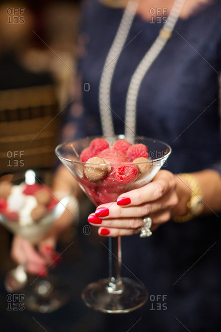 Woman holding raspberry frozen dessert in a martini glass
