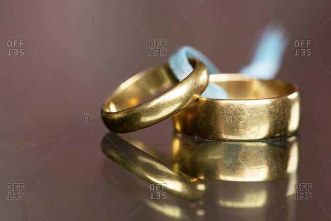 Simple gold wedding bands tied together with blue ribbon