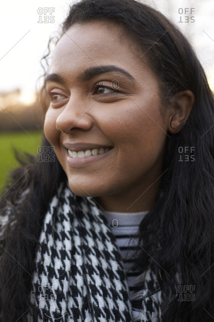 Head And Shoulders Portrait Of Young Woman Walking In Park