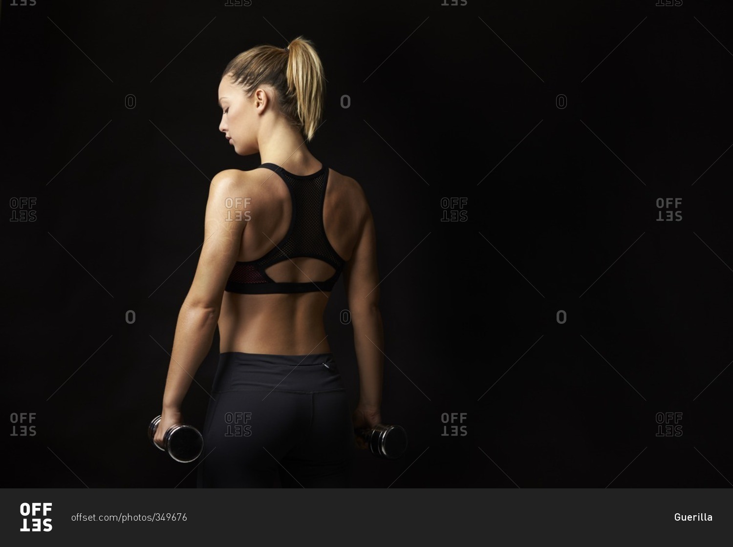 Blonde woman in sports clothing holding dumbbells, back view