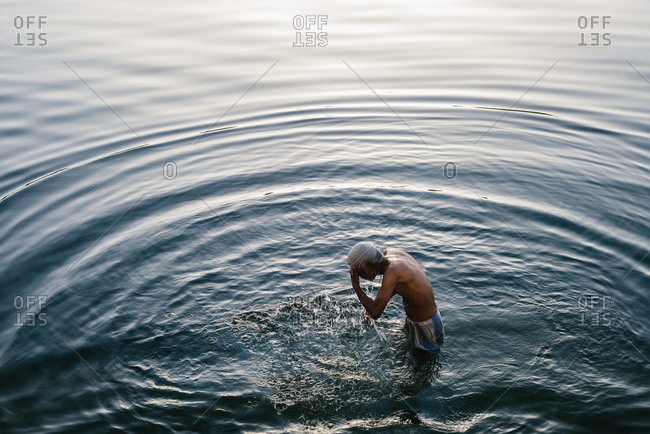 Udaipur, India - March 24, 2014: Man bathing in river at dusk, Udaipur, India