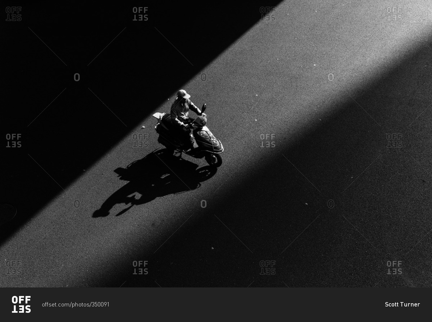 Overhead view of scooter rider passing through a ray of sunlight