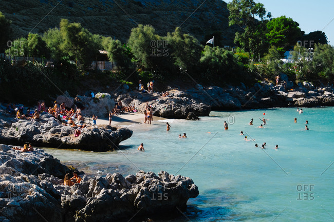 Palermo, Italy - August 17, 2015: Swimmers and beachgoers at rocky coast  of Palermo in Sicily